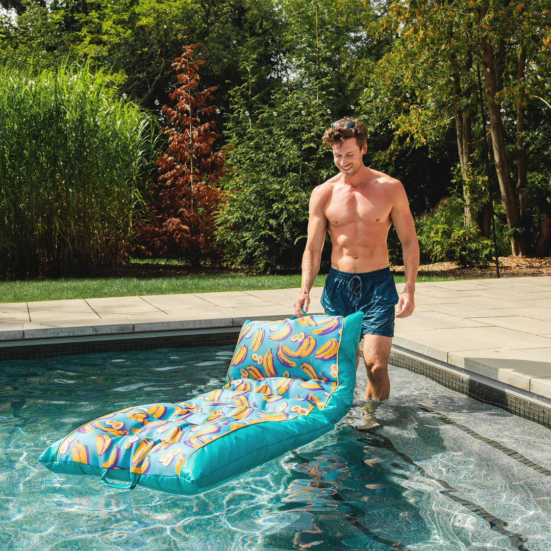 Man in pool setting down a pool float #color_banana-pop