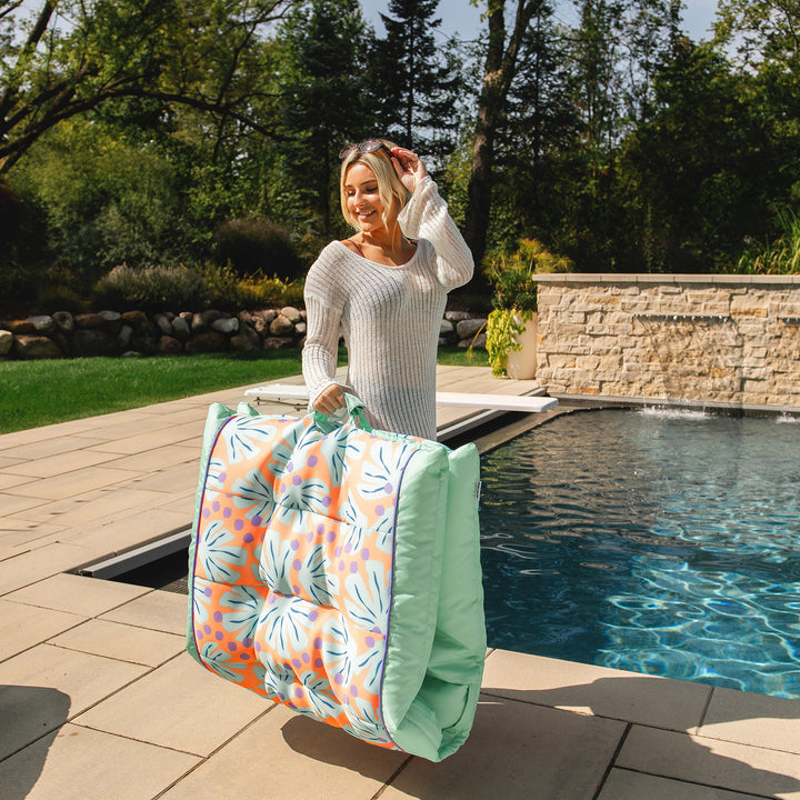 Woman holding a large pool float by a poolside #color_sweet-shells-peach