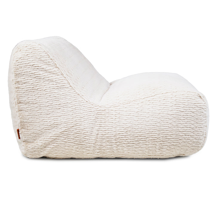 A cream-colored textured fabric lounge chair or bean bag chair, shown from a side profile view against a solid white background. 