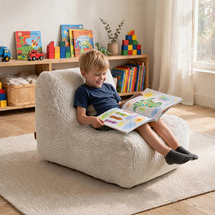 A young boy sits happily in a textured cream boucle children&
