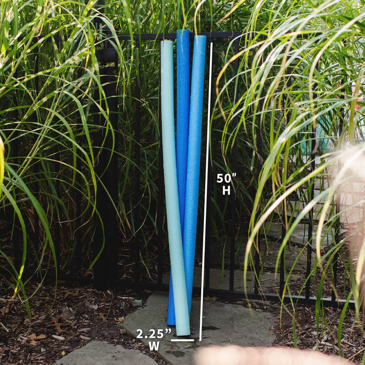 Three vertical pool noodles in light blue, medium blue, and navy are shown outdoors on a black metal rack, with white measurement lines and text indicating 50 inches high and 2.25 inches wide. 