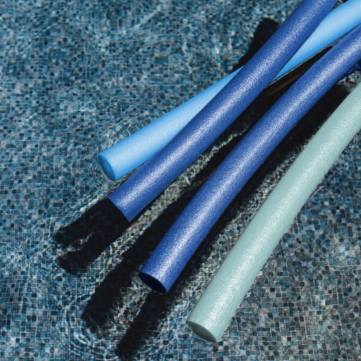 Three pool noodles in blue and mint green resting on a tiled swimming pool floor. 