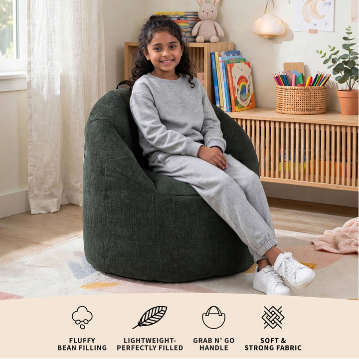 A child wearing a gray sweatshirt and matching sweatpants sits in a large, dark green bean bag chair in a brightly lit children&
