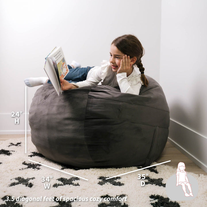 Child sitting on a bean bag chair reading a book with measurements displayed. #color_teddy-gray-plush