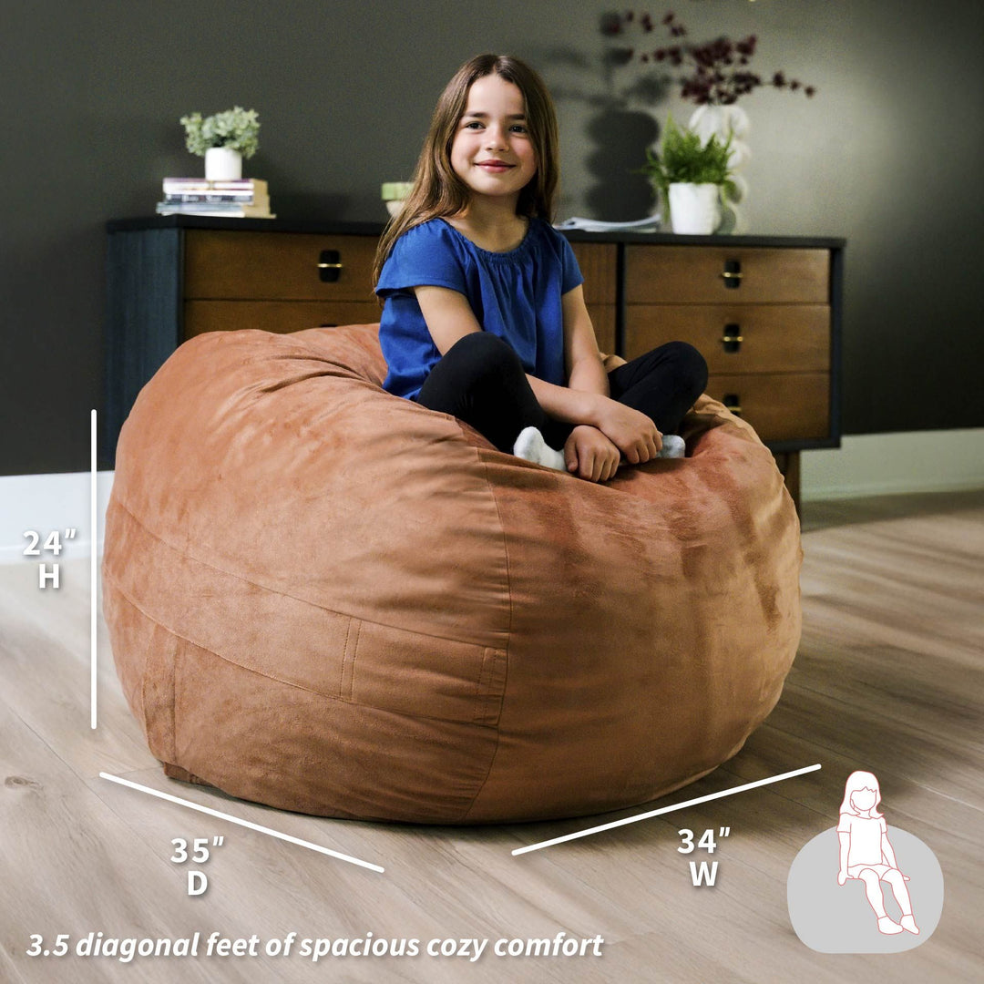 Child sitting on a large brown bean bag with dimensions displayed #color_copper-plush