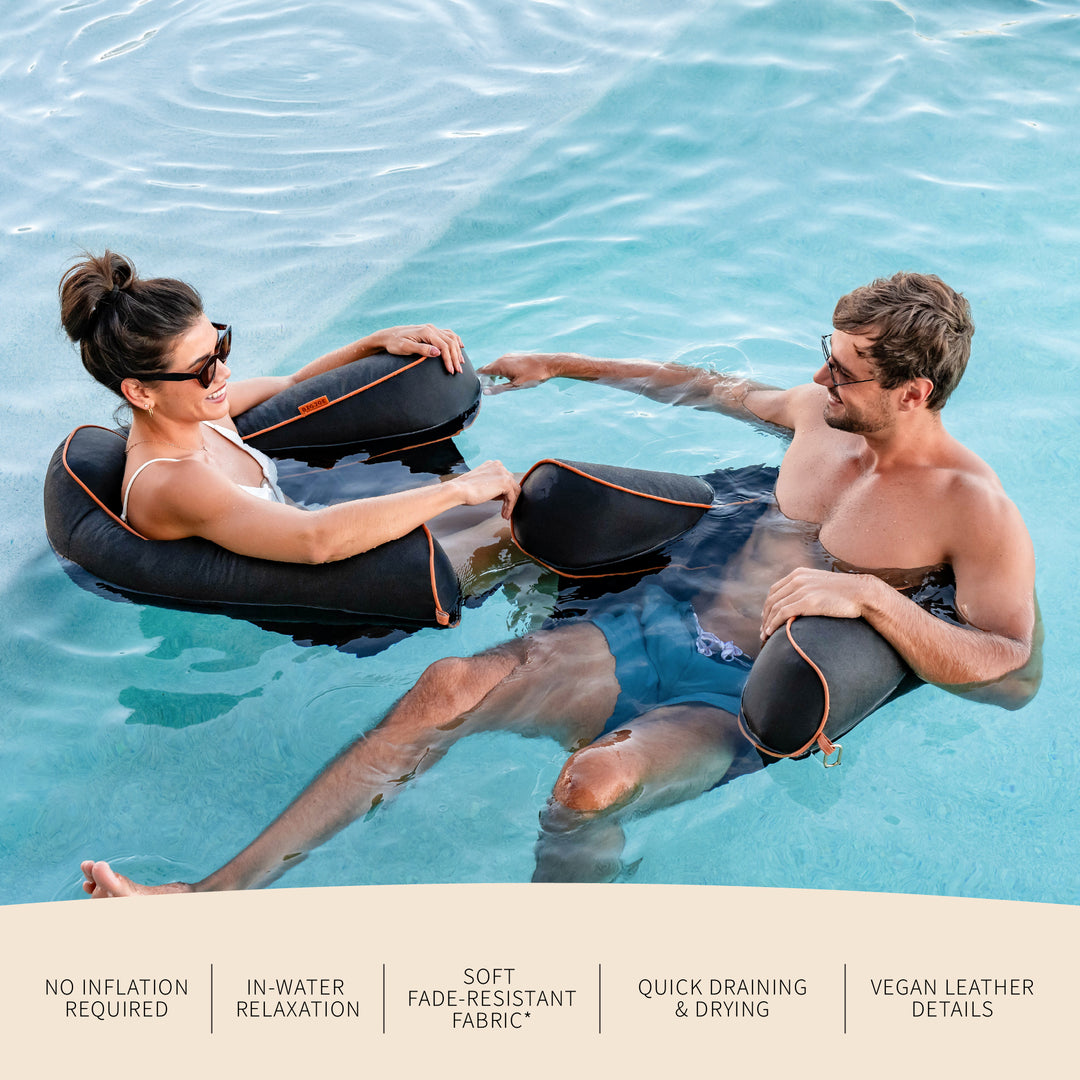 Two people relaxing in water with pool seats, surrounded by water. #color_twilight-sunbrella-fabric