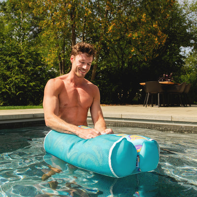 Man using a blue pool noodle in a swimming pool with trees and outdoor furniture in the background 