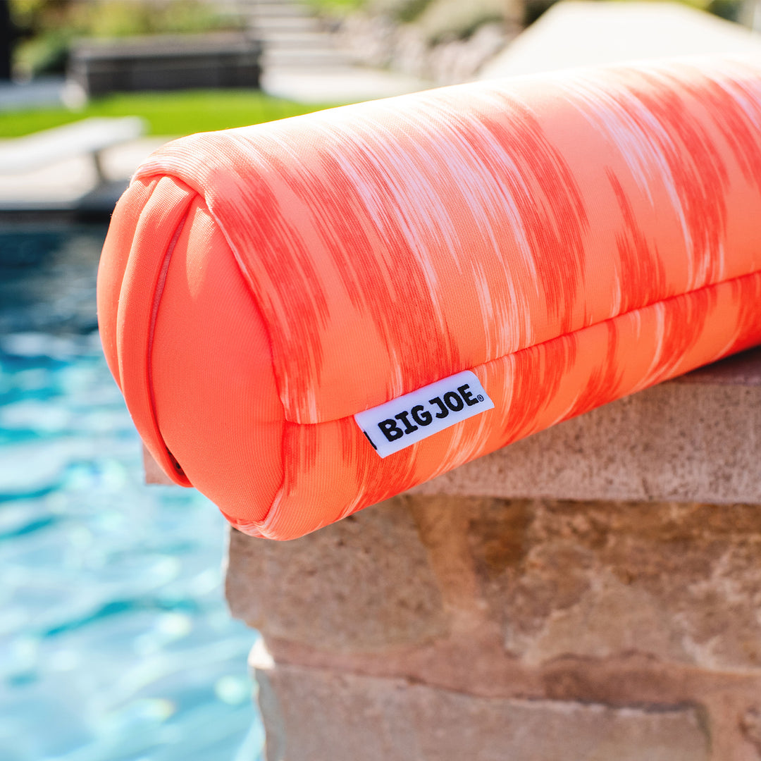 Orange striped pool noodle with 'BIGJOE' label by a pool #color_peach-glow