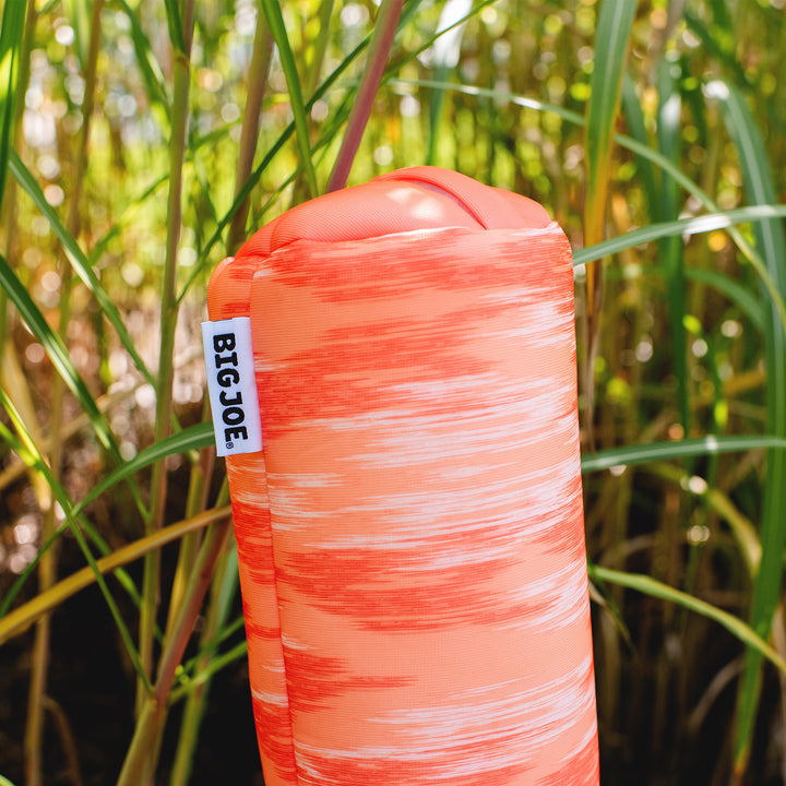 Orange pool noodle with 'BIG JOE' tag against a natural background #color_peach-glow