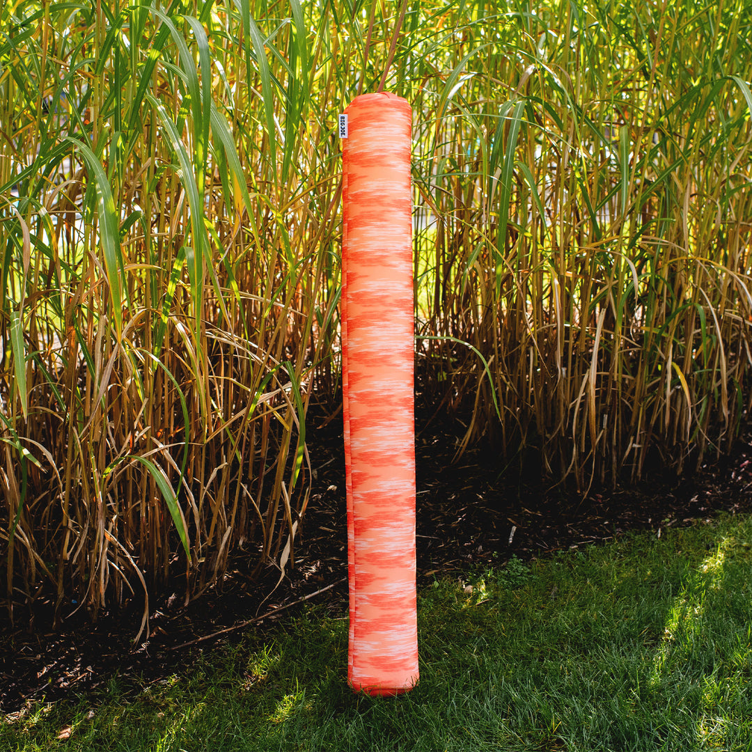 Red pool noodle in a grassy area #color_peach-glow