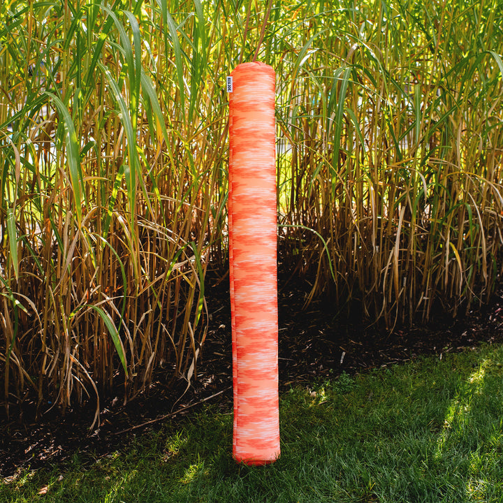 Red pool noodle in a grassy area #color_peach-glow