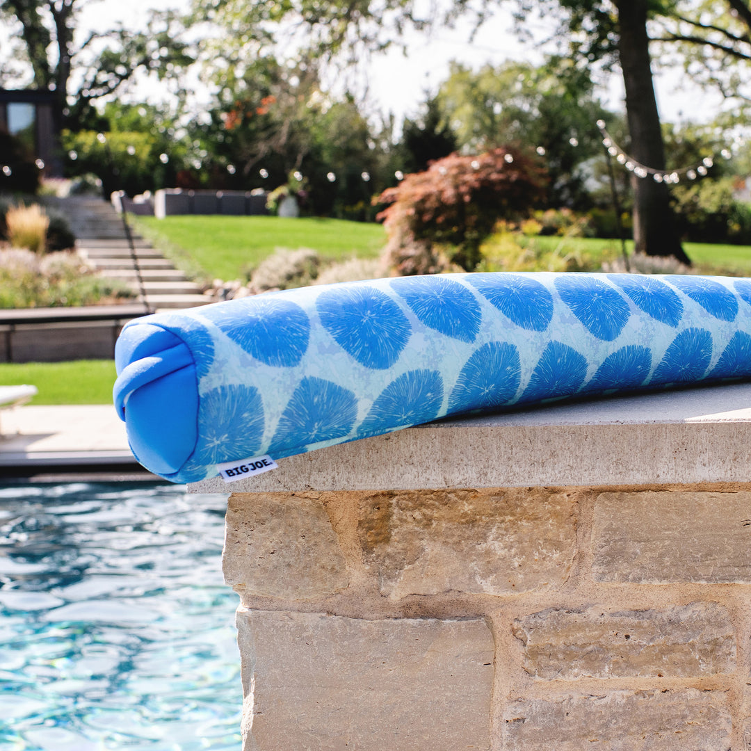 Blue pool noodle with white pattern on a stone ledge by a pool #color_coral-bloom