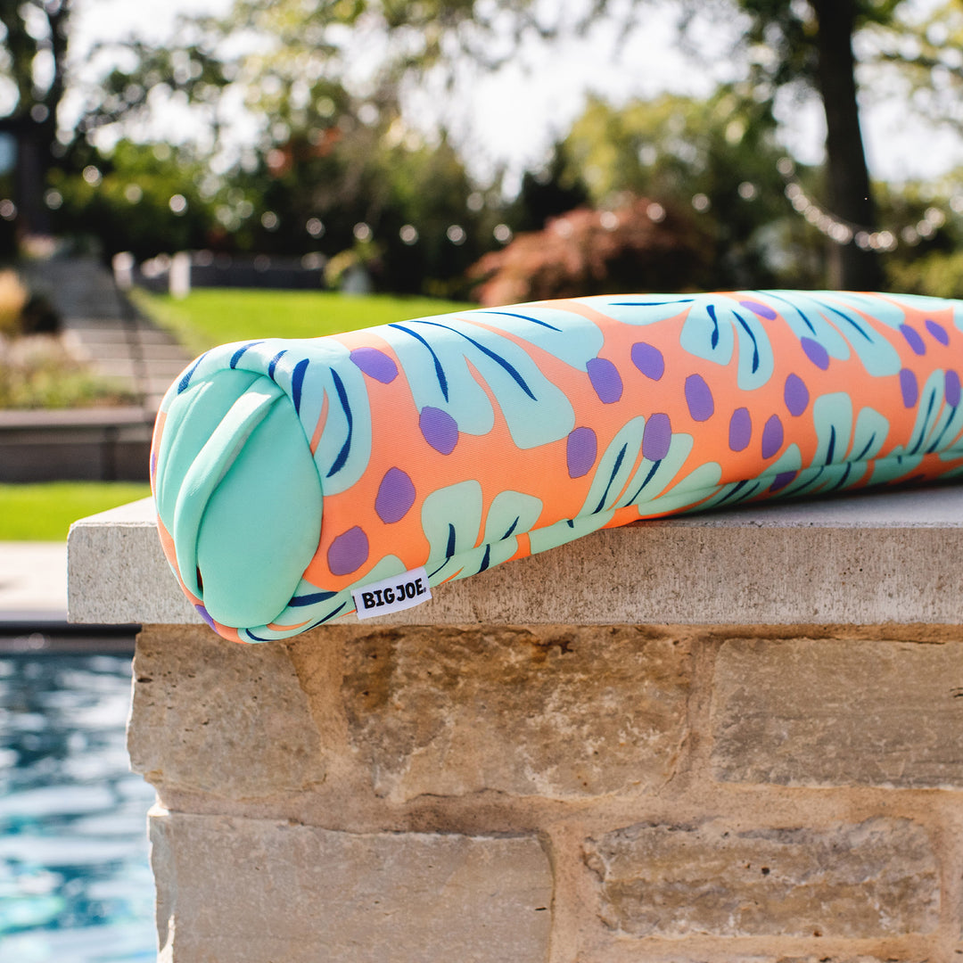 Colorful pool noodle with leaf pattern on a stone ledge by a pool #color_sweet-shells-peach