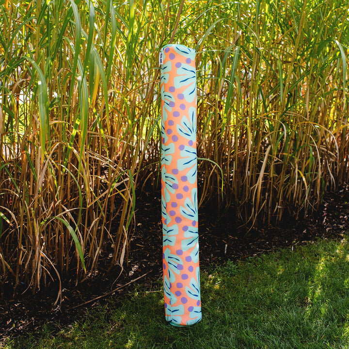 Colorful cylindrical pool float with a pattern standing in a field of tall grass. #color_sweet-shells-peach