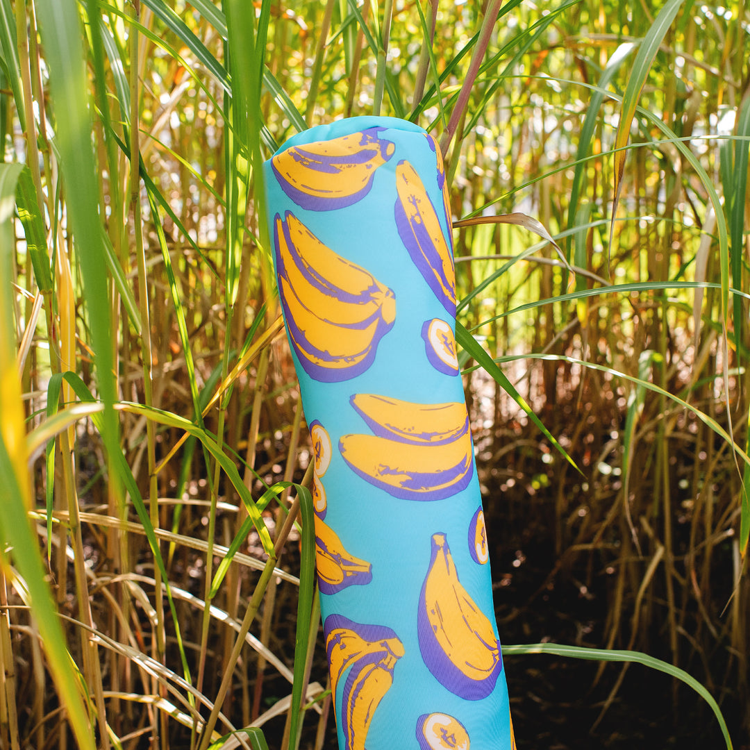 Blue pool float with banana pattern in a grassy field #color_banana-pop