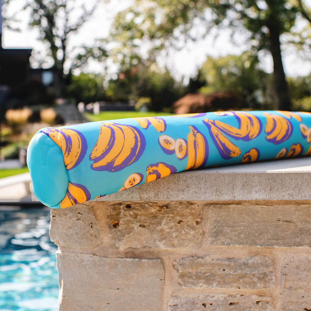 Pool noodle with banana pattern on a stone ledge by a pool #color_banana-pop