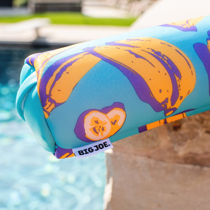 Colorful pool float with pumpkin design and 'BIG JOE' label by a pool. #color_banana-pop