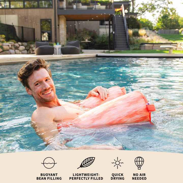 Man floating on a pink pool float in a swimming pool with text about product features. #color_peach-glow