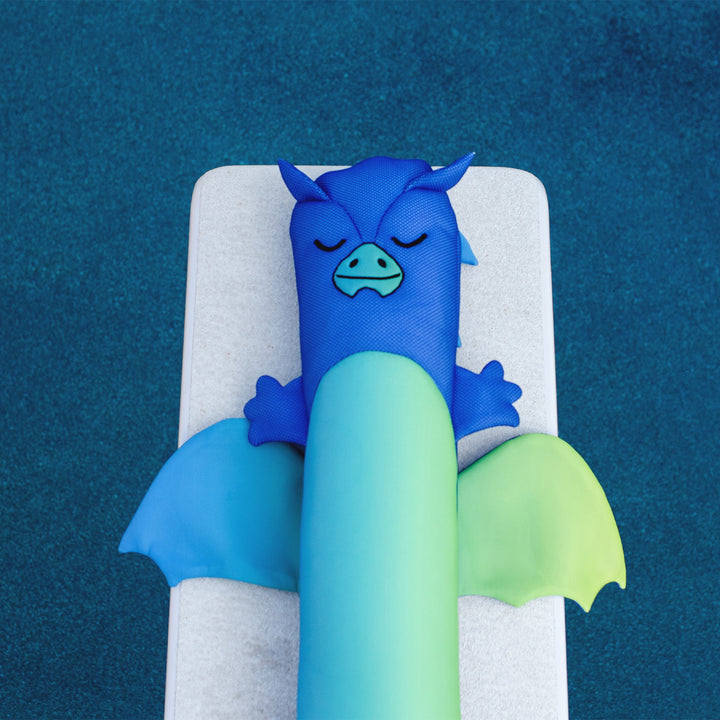 Blue and green dragon-like creature on a white pillow against a blue background #style_dragon