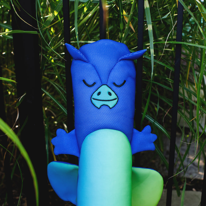 Blue and green plush toy with a face design held by a hand against a natural background #style_dragon