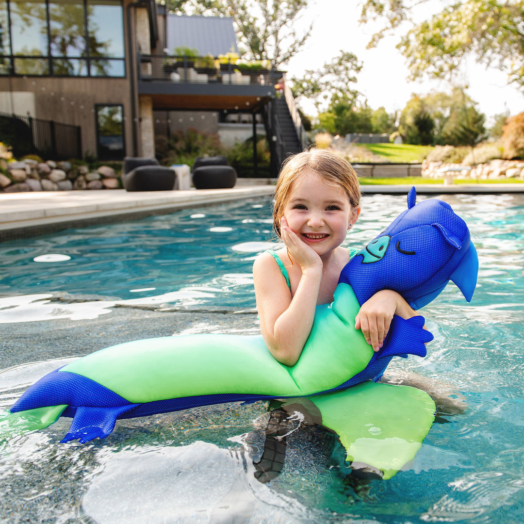 Child on a green and blue floatie dragon and mermaid tail in a pool #style_dragon