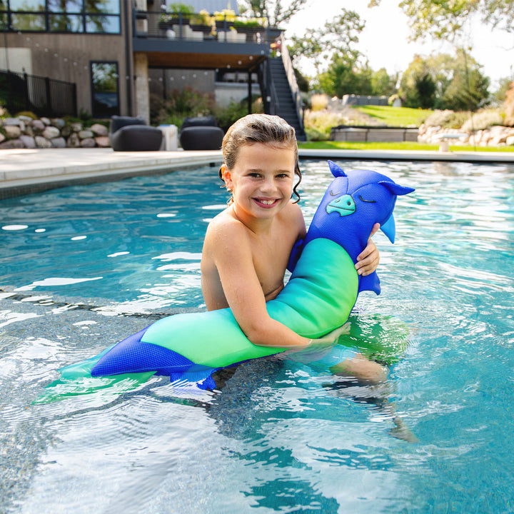 Child holding a blue and green dragon with mermaid tail toy in a pool. #style_dragon