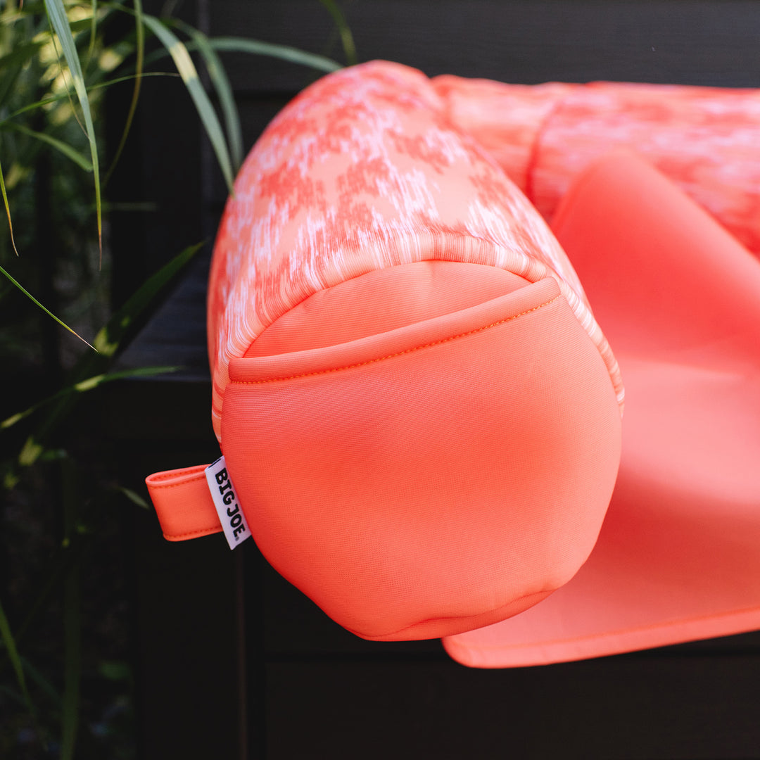 Close-up of a pink pool float with a visible brand tag against a dark background. #color_peach-glow