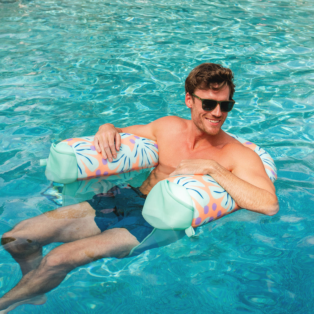 Man floating on a colorful ring in a pool #color_sweet-shells-peach