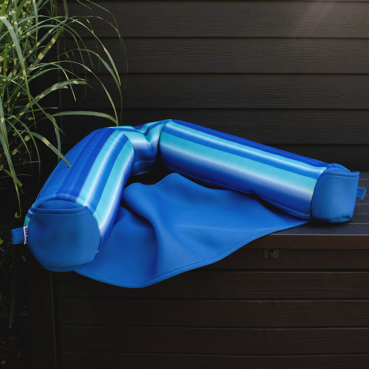 Blue pillow float on a wooden surface with a plant in the background #color_blurred-blue