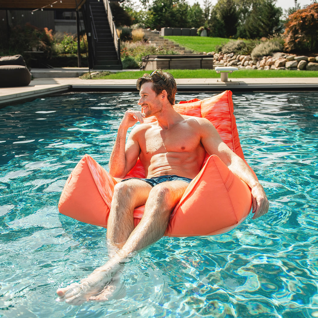 Man relaxing on an orange chair in a pool #color_peach-glow