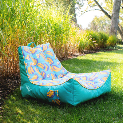 Turquoise bean bag chair with banana pattern on grass 