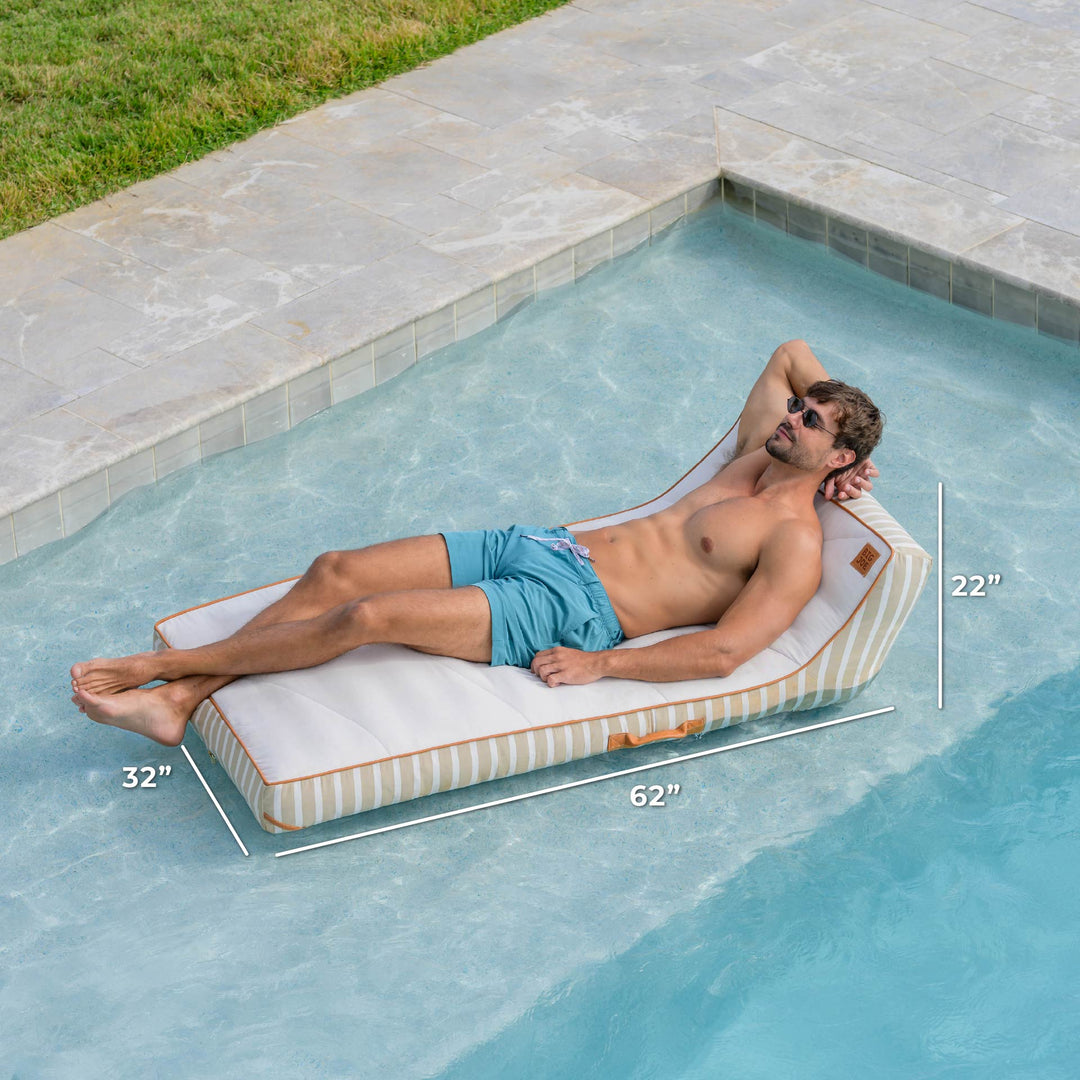 Man lying on a rectangular pool float with dimensions labeled, by a pool. #color_sand-stripe-sunbrella-fabric