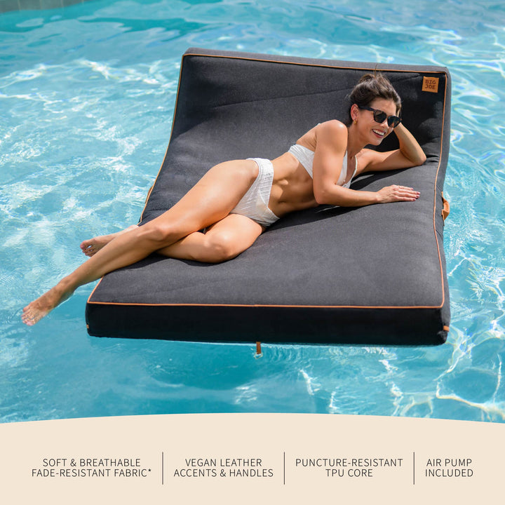 Person lying on a floating mat in a pool with product features listed below. #color_twilight-sunbrella-fabric