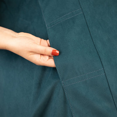 Hand touching teal fabric with a focus on texture and color. 