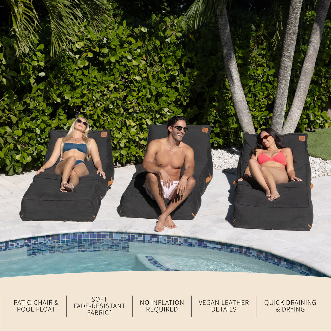 Three people relaxing on black pool chairs by a pool with greenery in the background. #color_twilight-sunbrella-fabric