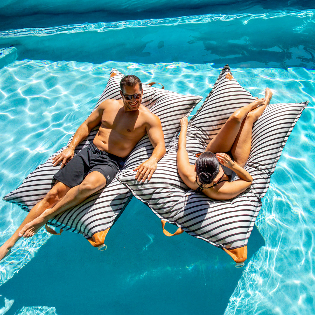 Couple relaxing on their Lux Lagoon Lounger Pool Floats #color_black-and-white-cape-stripe