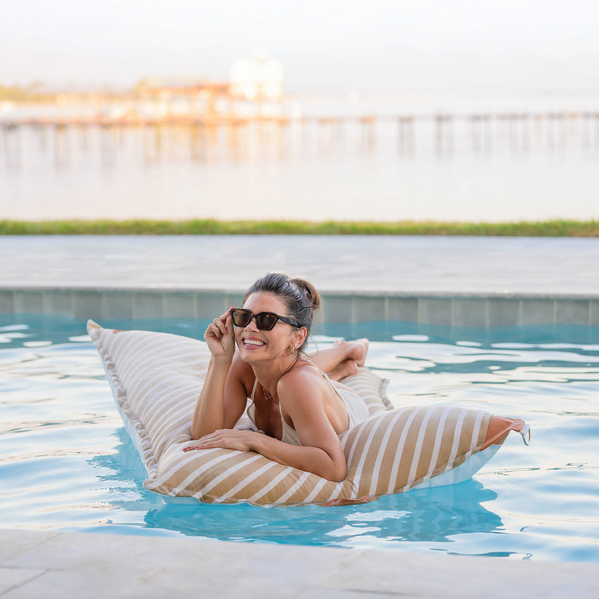 Woman lounging on a striped inflatable pool float in a pool. 