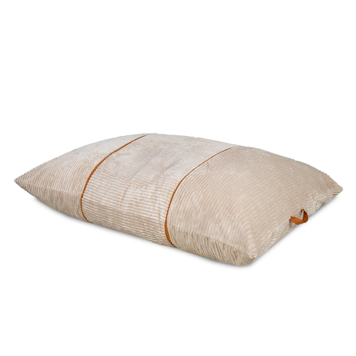 A rectangular lumbar pillow in a textured beige corduroy fabric, featuring a central vertical stripe with a thin brown leather accent and a matching leather loop on the side. 