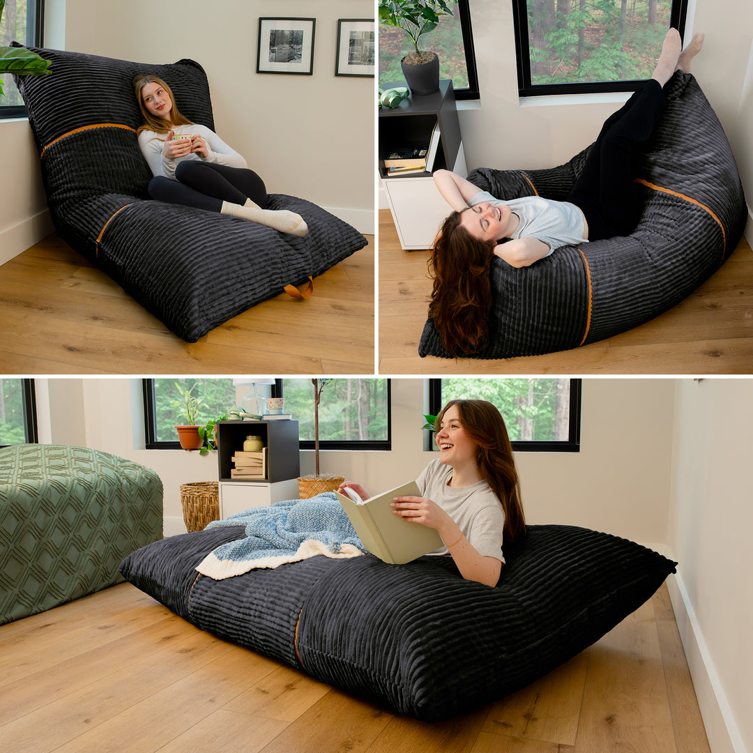 Three-panel collage showing a woman reclining on a large floor bean bag chair in a bright room with wood floors and windows. The bean bag is dark charcoal gray with subtle vertical texture and thin tan piping accents. 