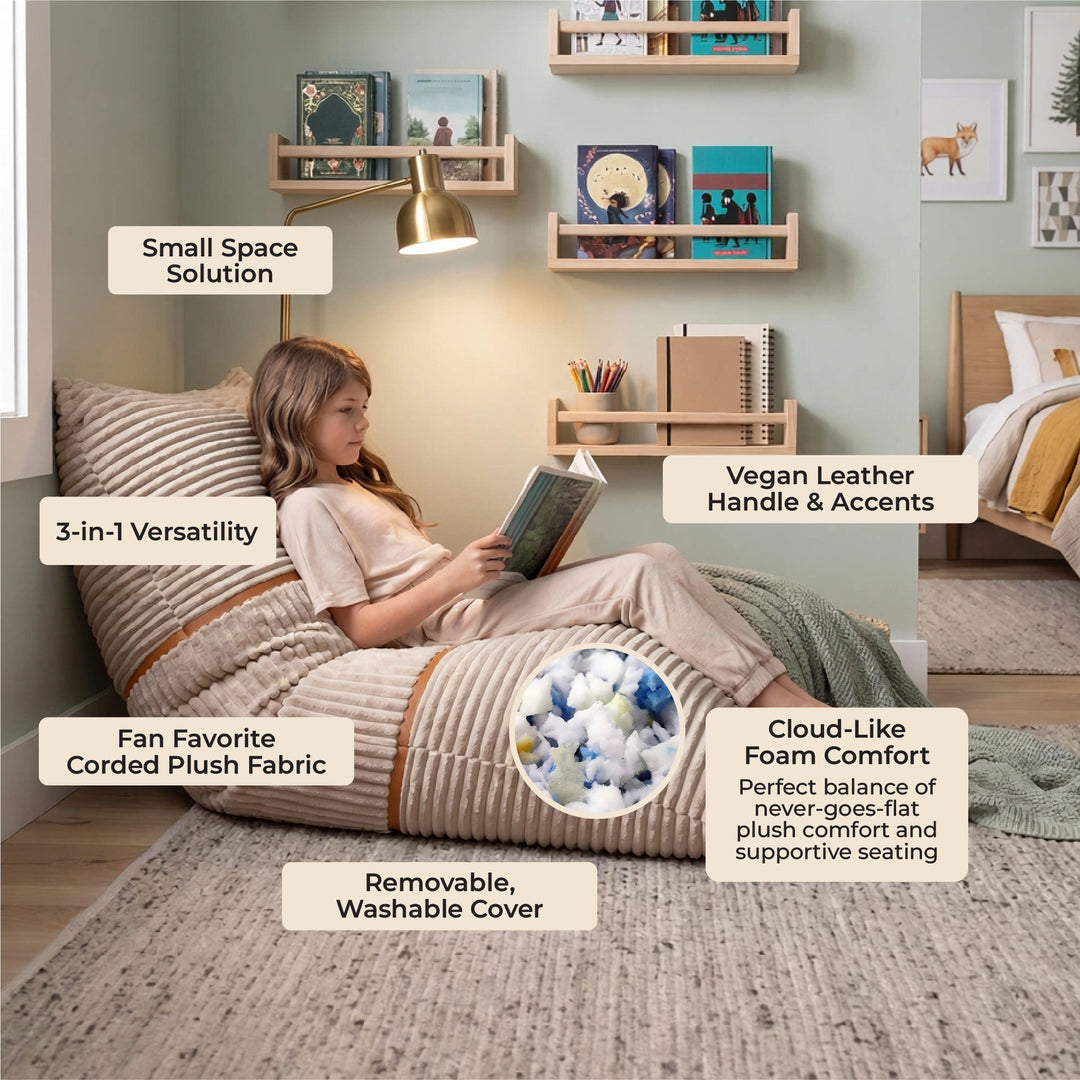 A child sits on a large upholstered bean bag chair in a styled bedroom. The bean bag has a beige corded fabric cover with a striped pattern and a matching handle. 