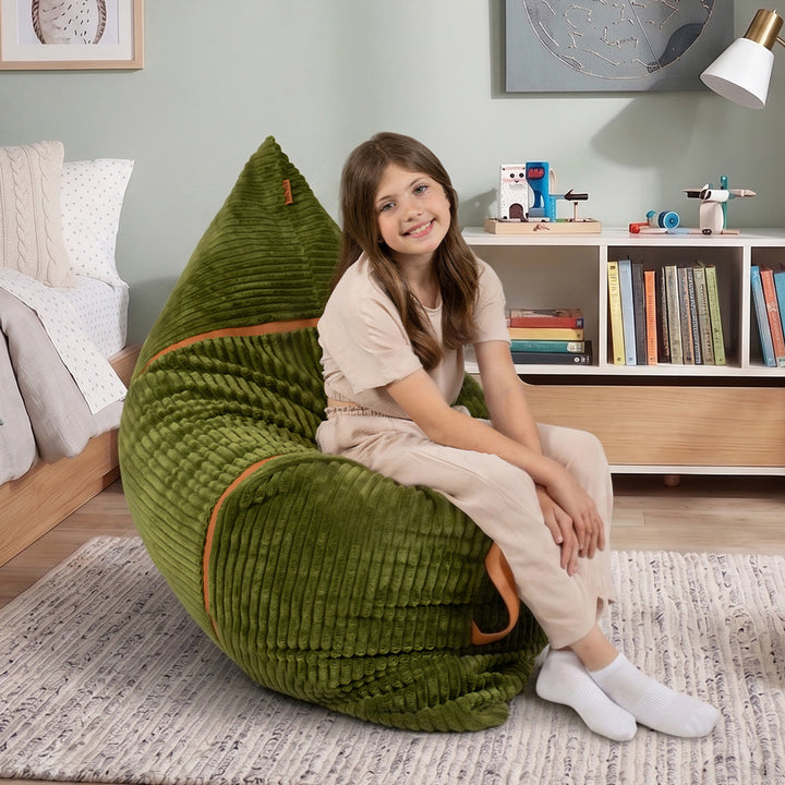 A young girl with long brown hair sits smiling on a large, plush olive green bean bag chair in a child&