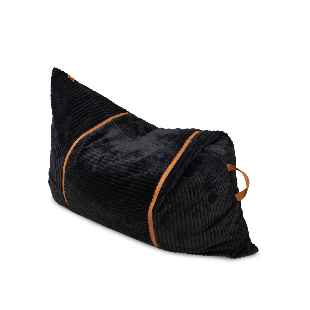 A black corduroy bean bag chair with contrasting tan-brown piping and a matching carry handle, shown on a solid white background. 