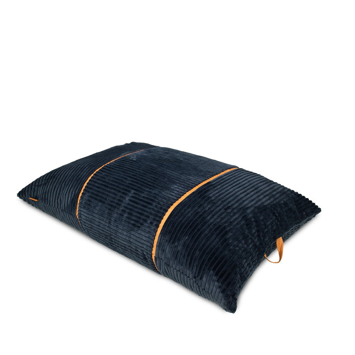 A dark navy blue corduroy pillow with contrasting orange-brown piping and a matching fabric loop, shown on a plain white background. 