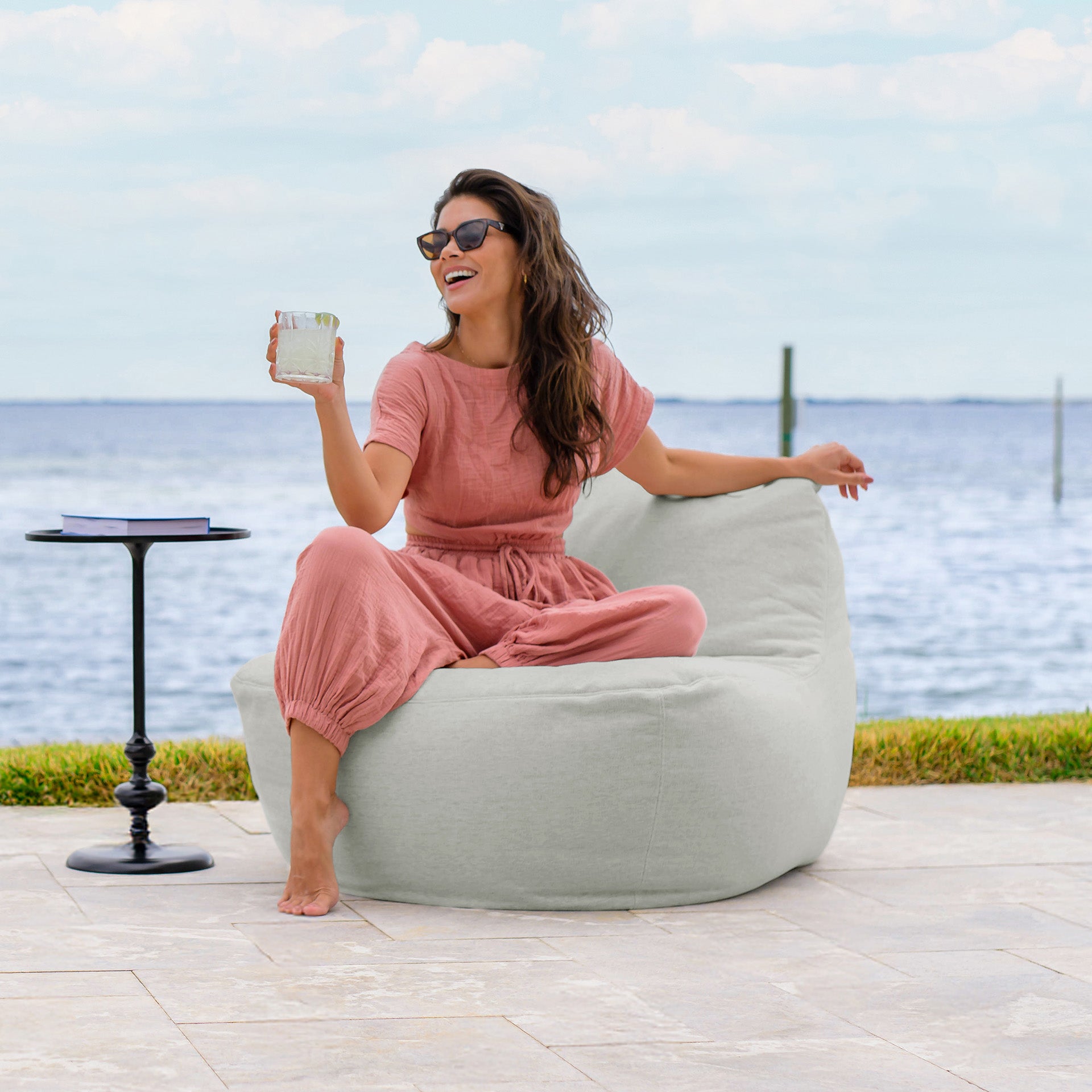 Woman enjoying herself on the patio on a Luft Patio Chair #color_sunday-gray-outdoor-performance-linen