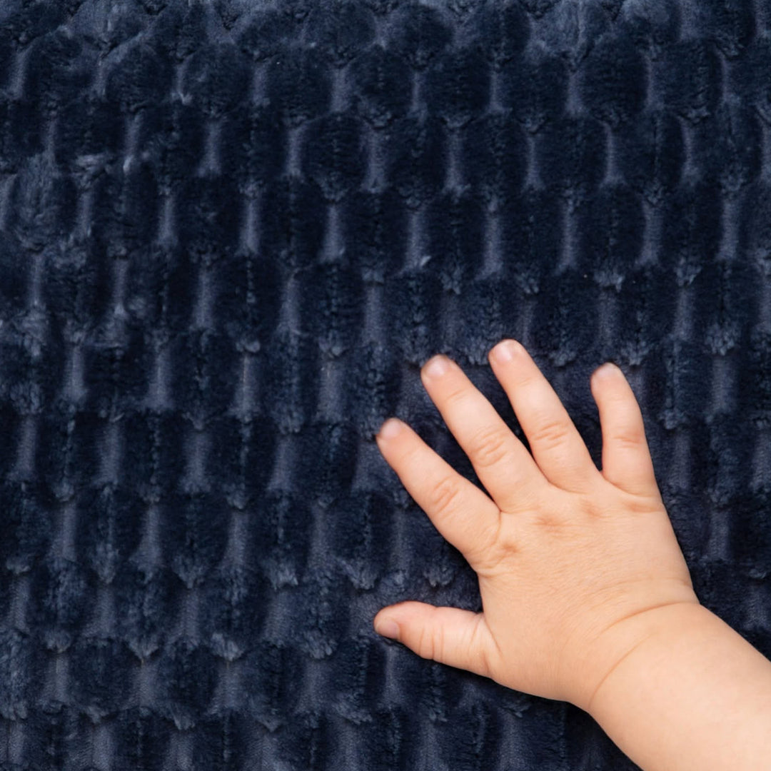 A close-up of a dark navy blue textured fabric with a child&