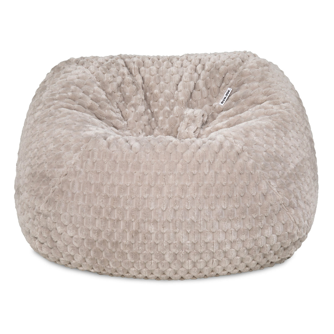 A round, plush bean bag chair in a textured, waffle-like fabric, shown against a plain white background. The color is a warm, light taupe-beige. 