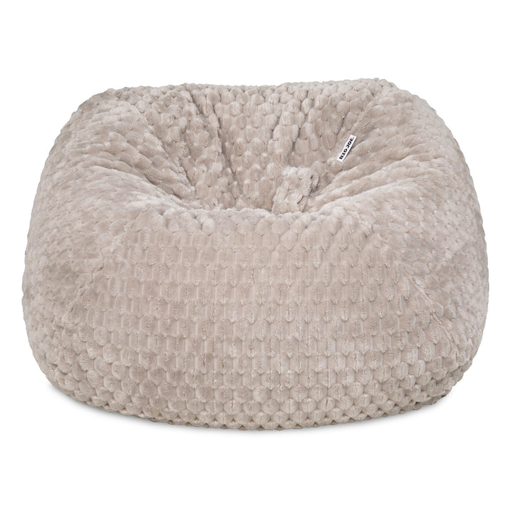 A round, plush bean bag chair in a textured, waffle-like fabric, shown against a plain white background. The color is a warm, light taupe-beige. 