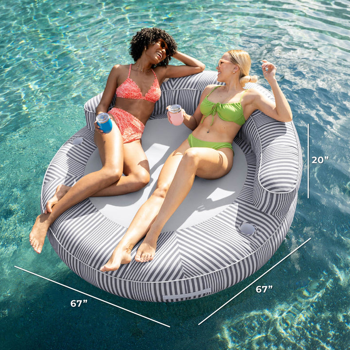 Two women relaxing on a circular pool float with measurements displayed. #color_shoreline-gray-stripe-olefin