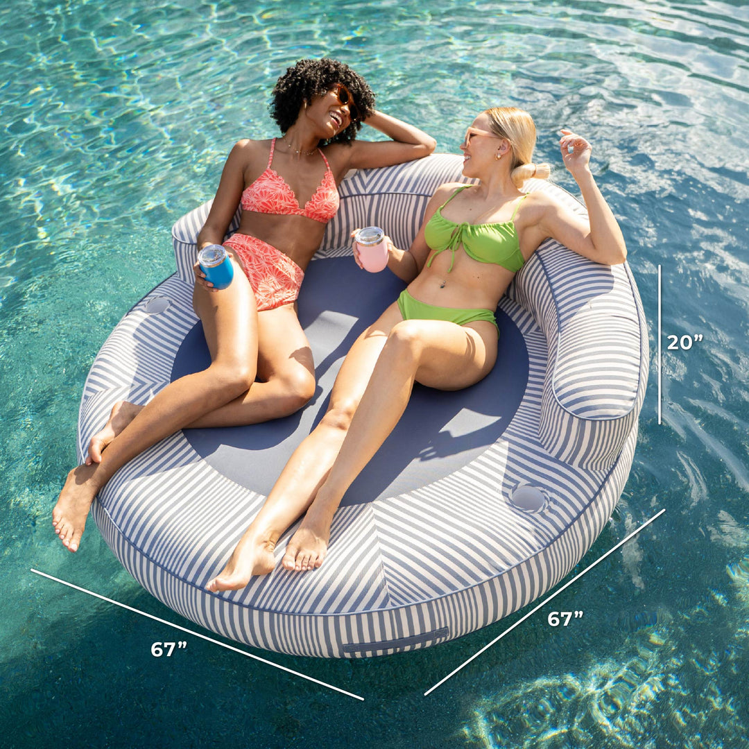 Two women lounging on a circular striped pool float with measurements displayed. #color_weekend-navy-stripe-olefin