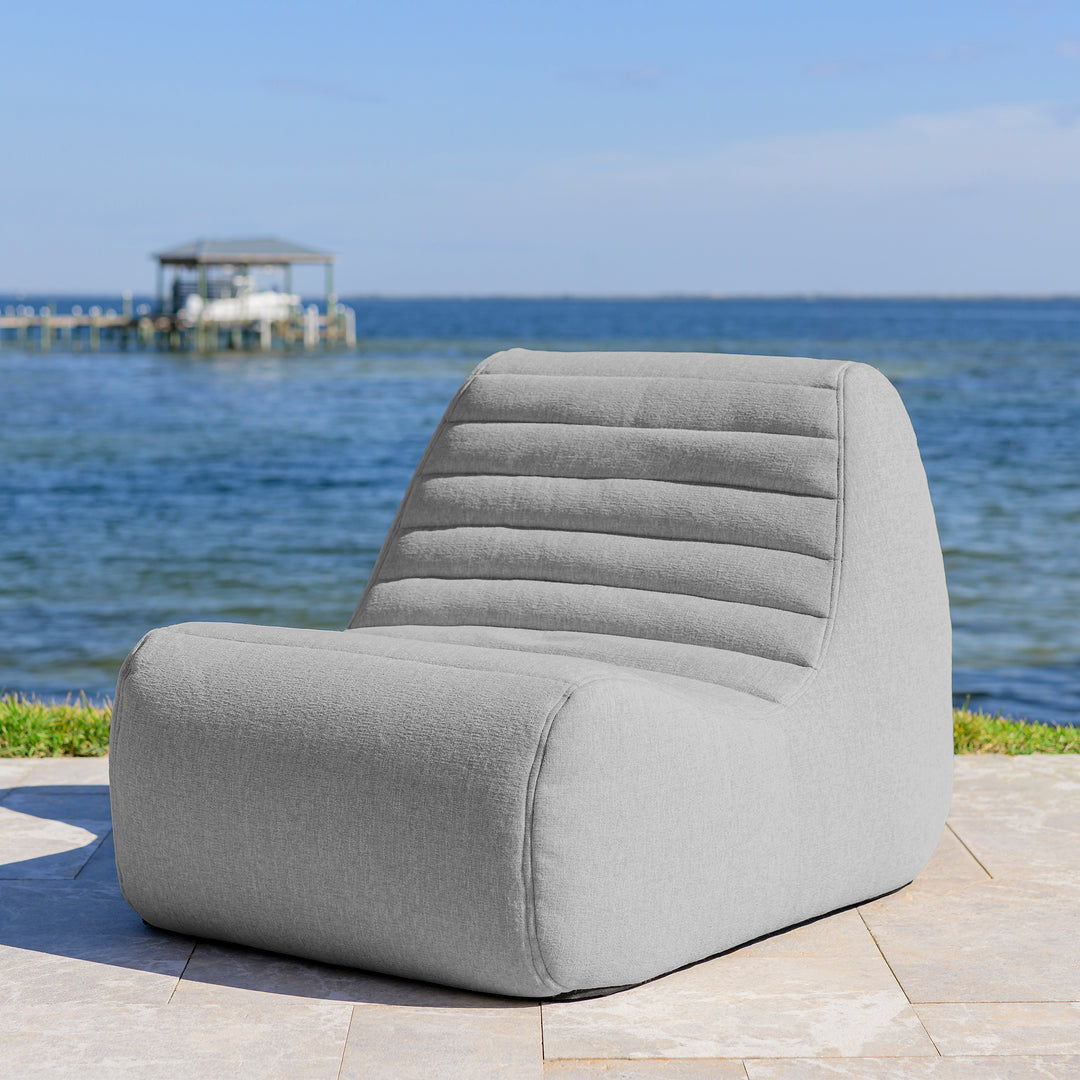 Gray chair on a patio with a scenic view of water and dock in the background #color_port-gray-outdoor-performance-linen